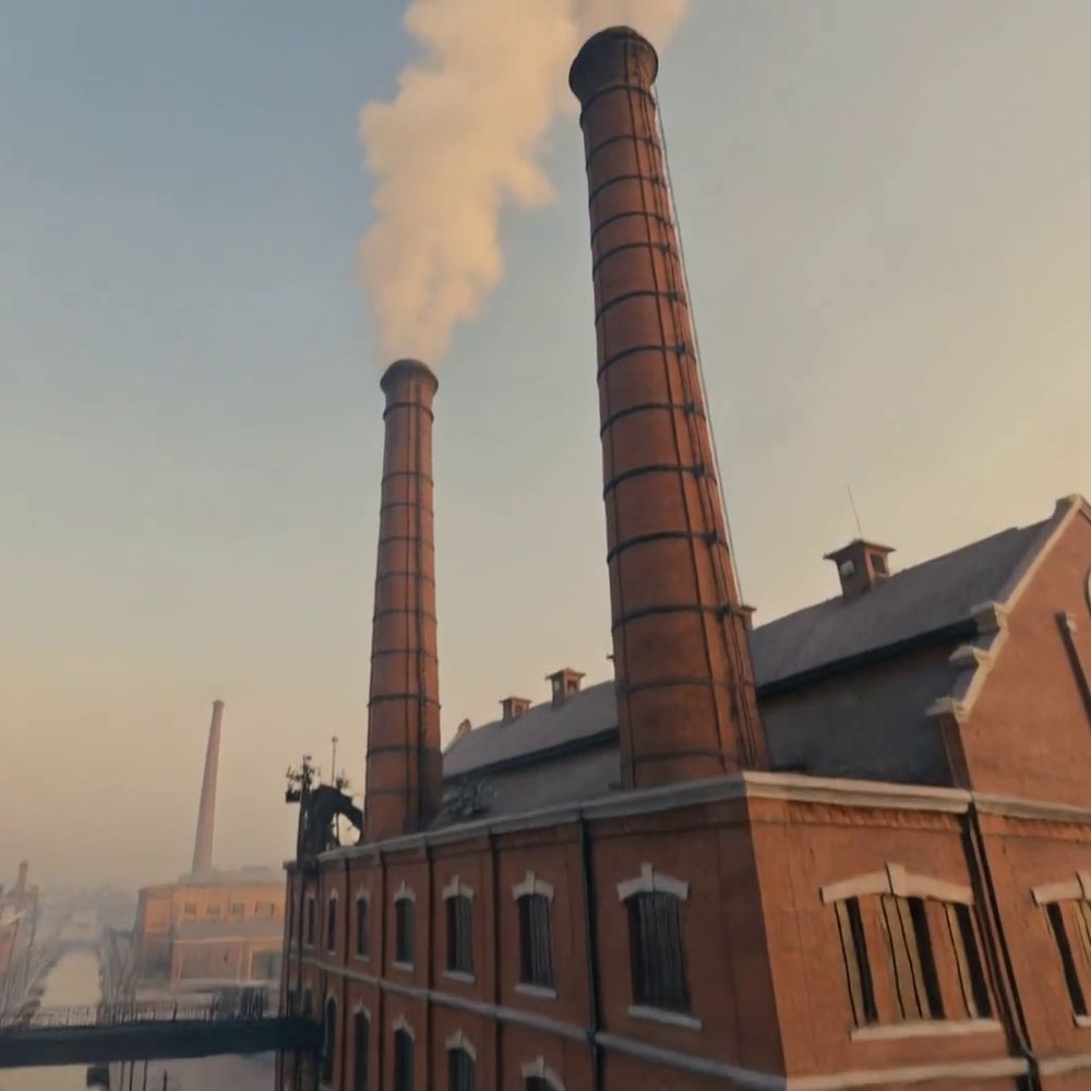 Factory chimneys trailing smoke above a brick mill
